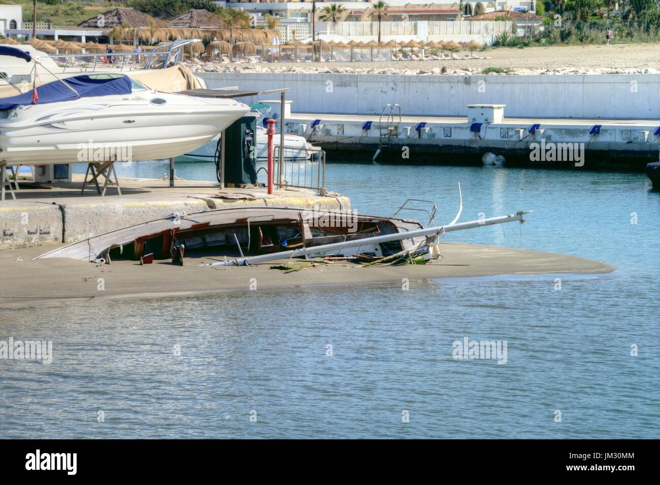 Gesunkenes Segelboot gefangen im Sand nach einem Sturm am Eingang zum Hafen von Cabopino. Stockfoto