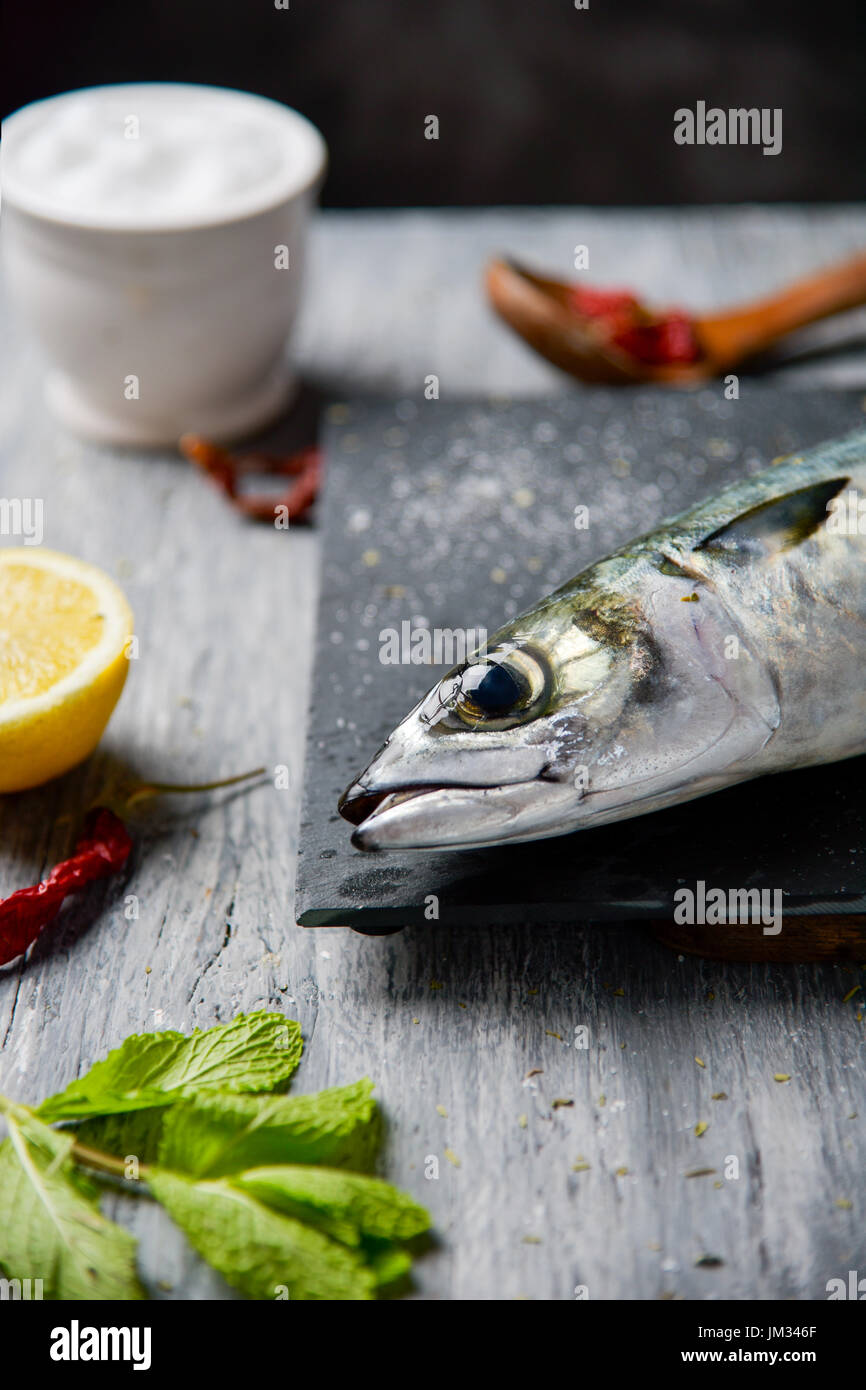 Nahaufnahme von einer rohen frische Makrele auf einem Schiefer Tablett platziert auf einem grauen rustikalen Holztisch Stockfoto