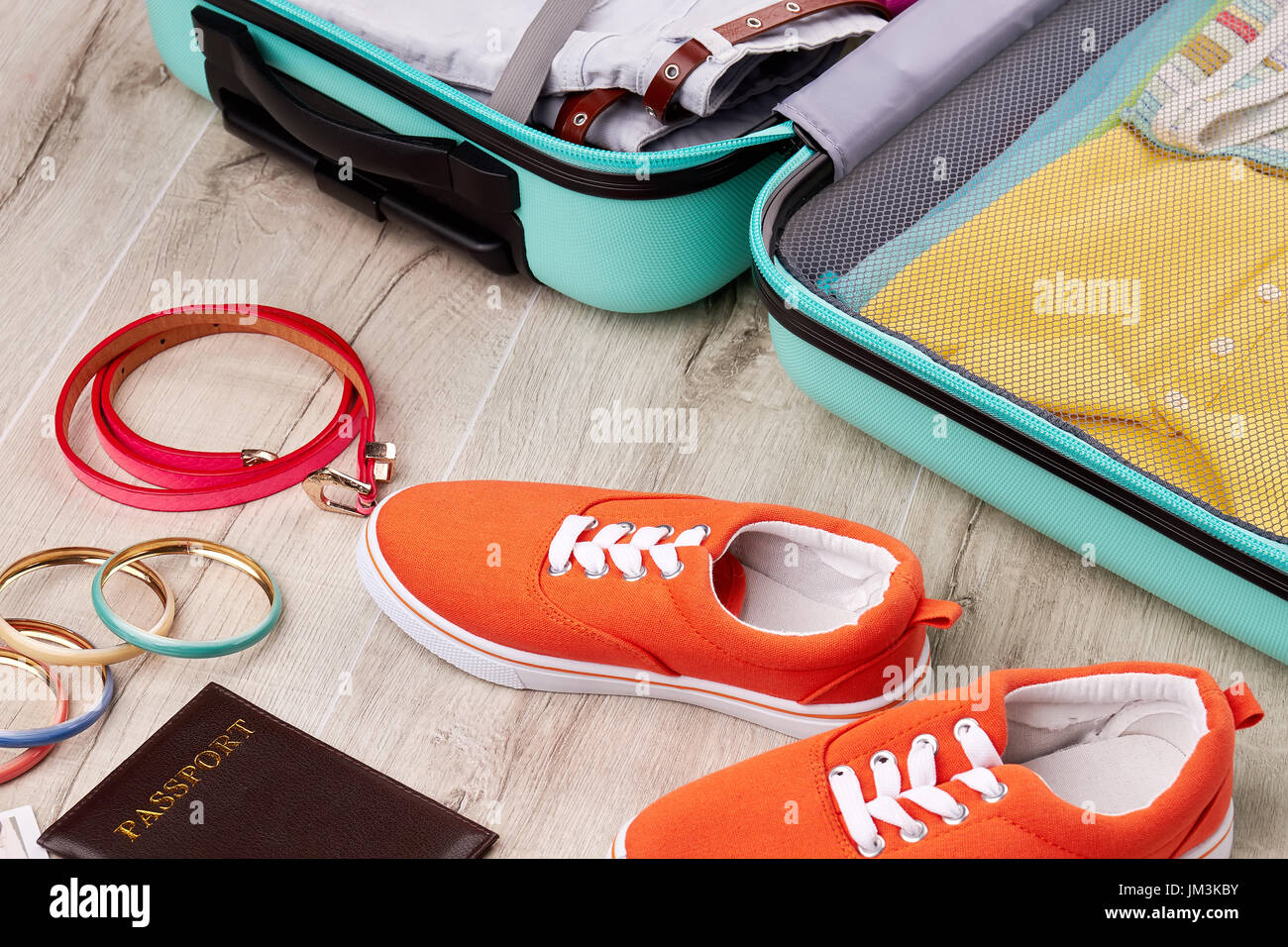 Farbige Turnschuhe in der Nähe von geöffneten Koffer. Wesentliche Elemente für die Sommerferien. Bequeme Schuhe für die Reise. Stockfoto