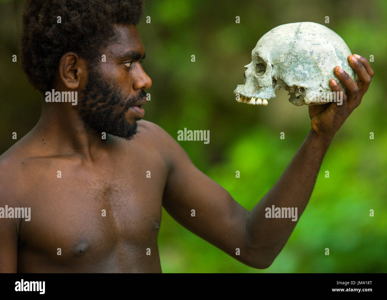 Mann hält einen menschlichen Schädel in Amelbati Kannibale Website, Provinz Malampa, Malekula Insel, Vanuatu Stockfoto