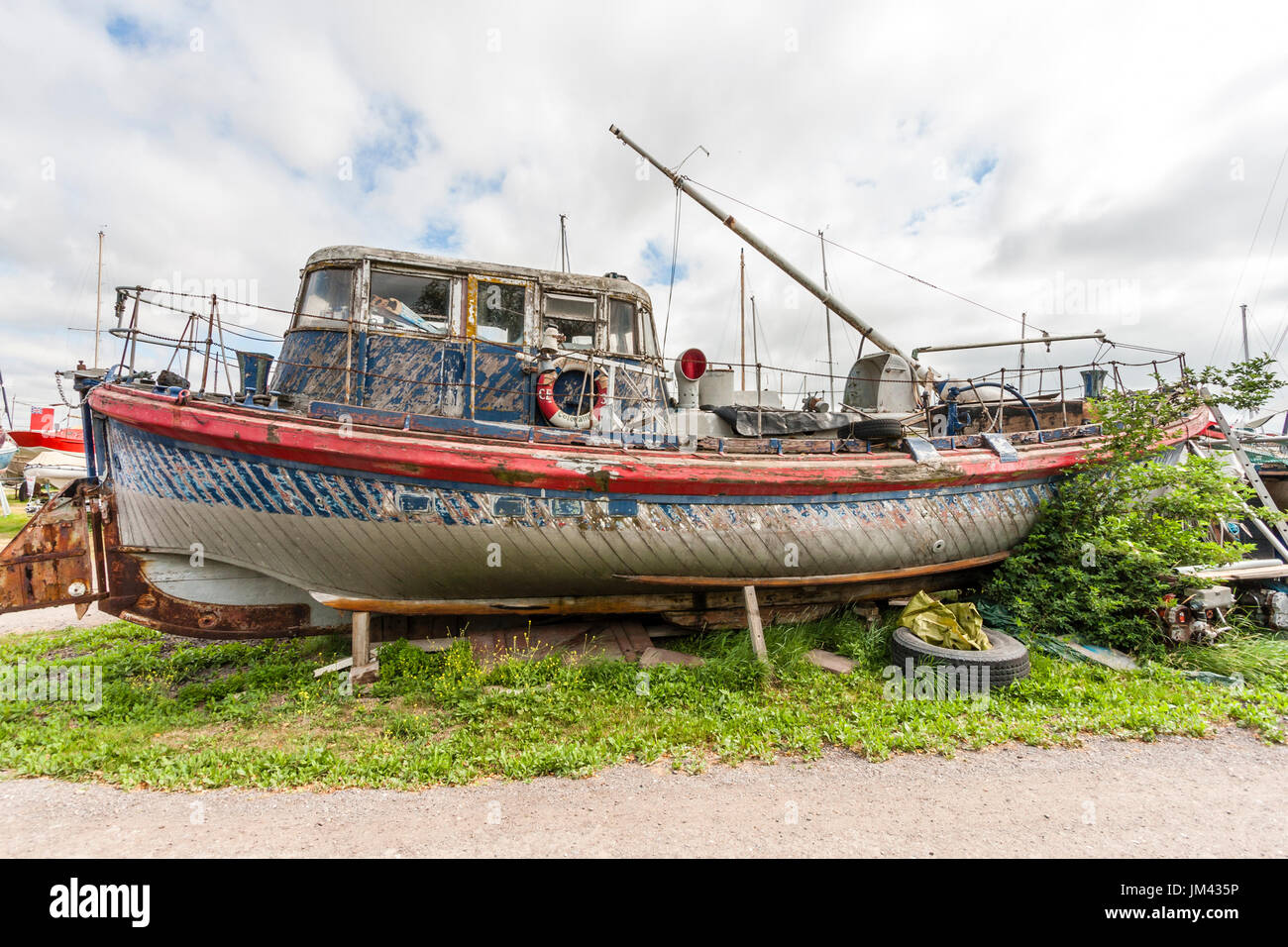 Seitenansicht des ehemaligen Rettungsboot, "London" trocken - auf dem Land und im desolaten Zustand mit sehr verwitterte blaue und rote Lackierung angedockt. Stockfoto