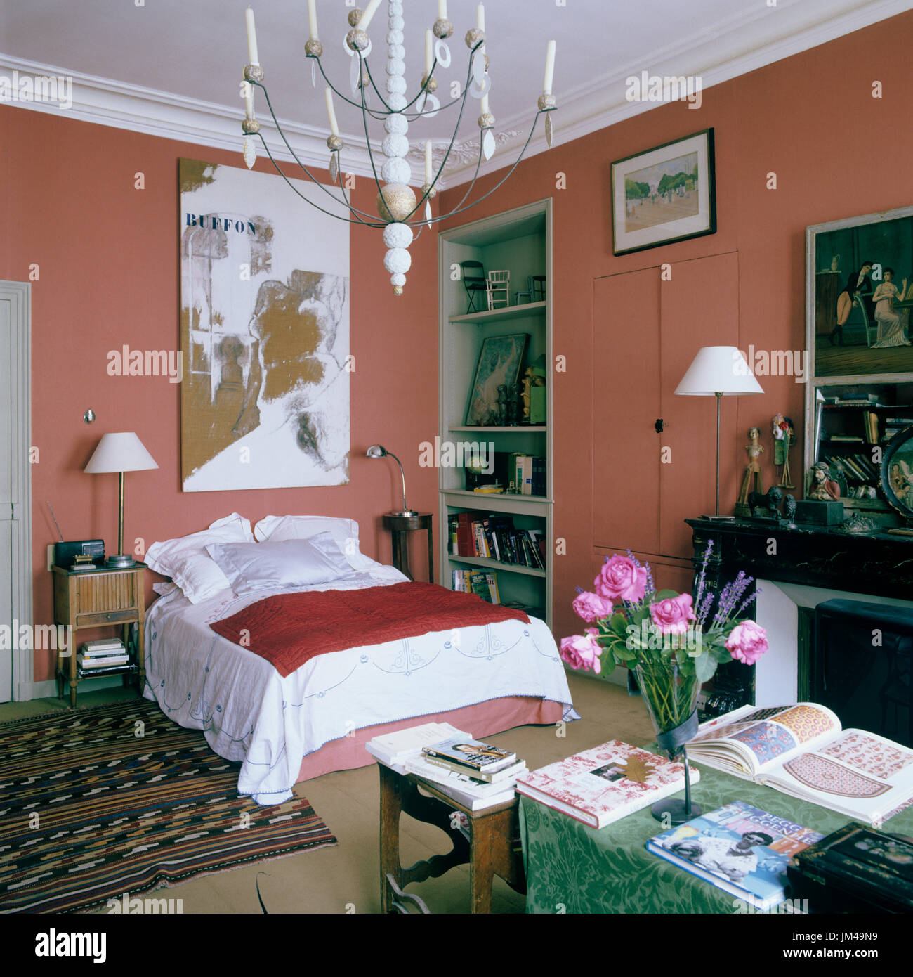 Grafik über Doppelbett mit Schnittblumen auf Schreibtisch Stockfoto