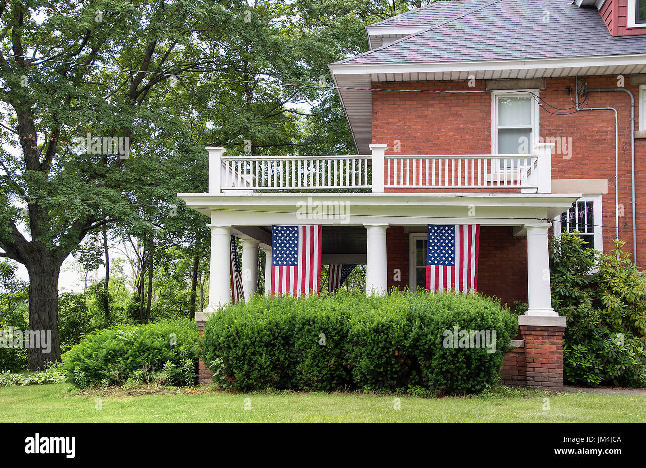 alten Backsteinhaus mit hängenden amerikanische Flagge auf Veranda Stockfoto