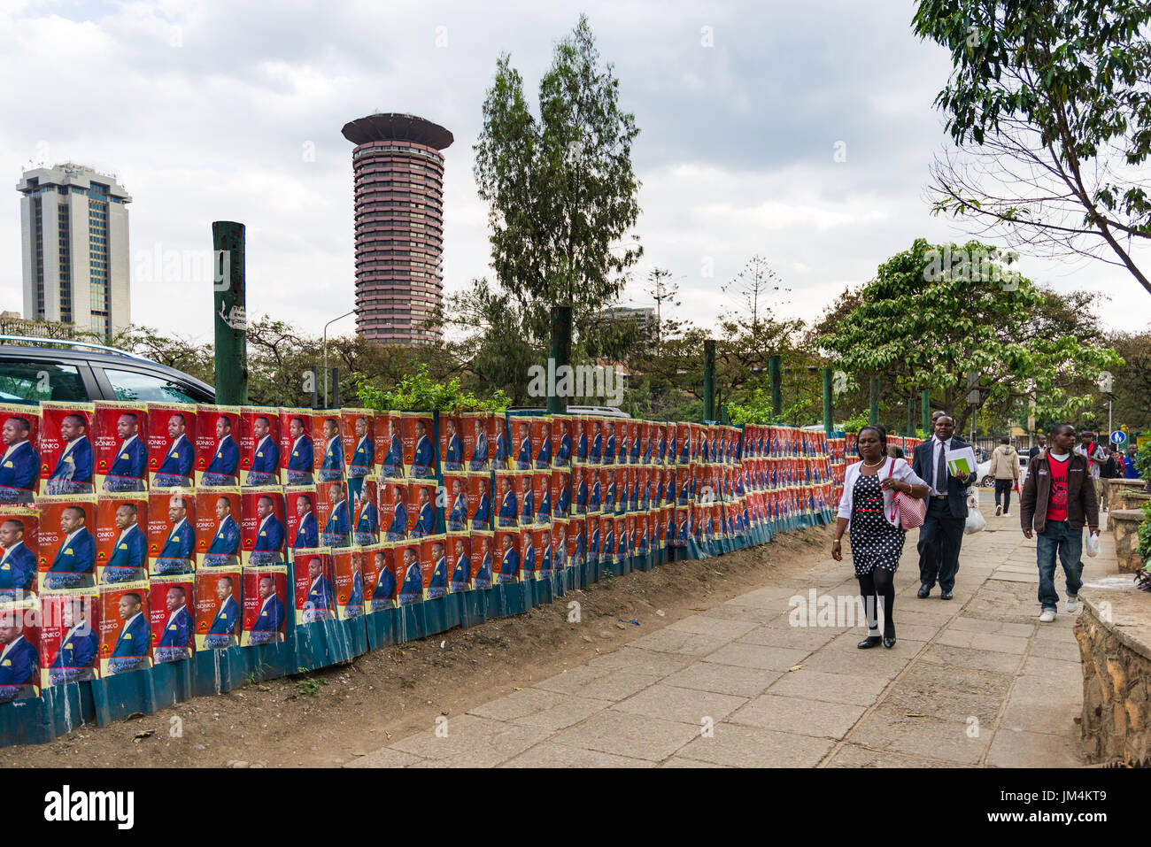 Menschen zu Fuß letzten Kenianischen Wahlkandidaten Poster an der Wand in Nairobi City mit Kenyatta International Convention Center im Hintergrund, Kenia Stockfoto