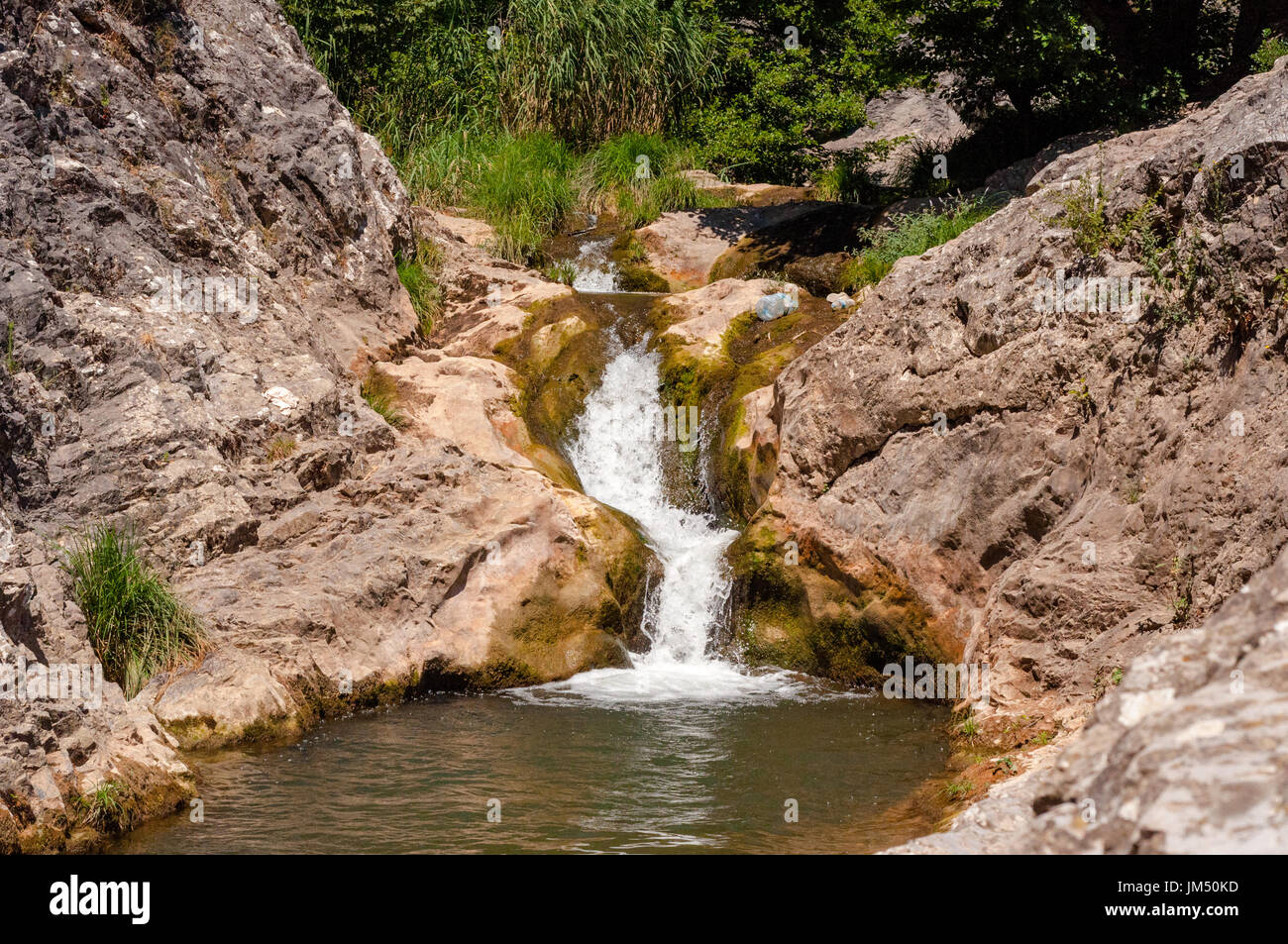 Kleiner Wasserfall läuft durch felsiges Gelände Stockfoto