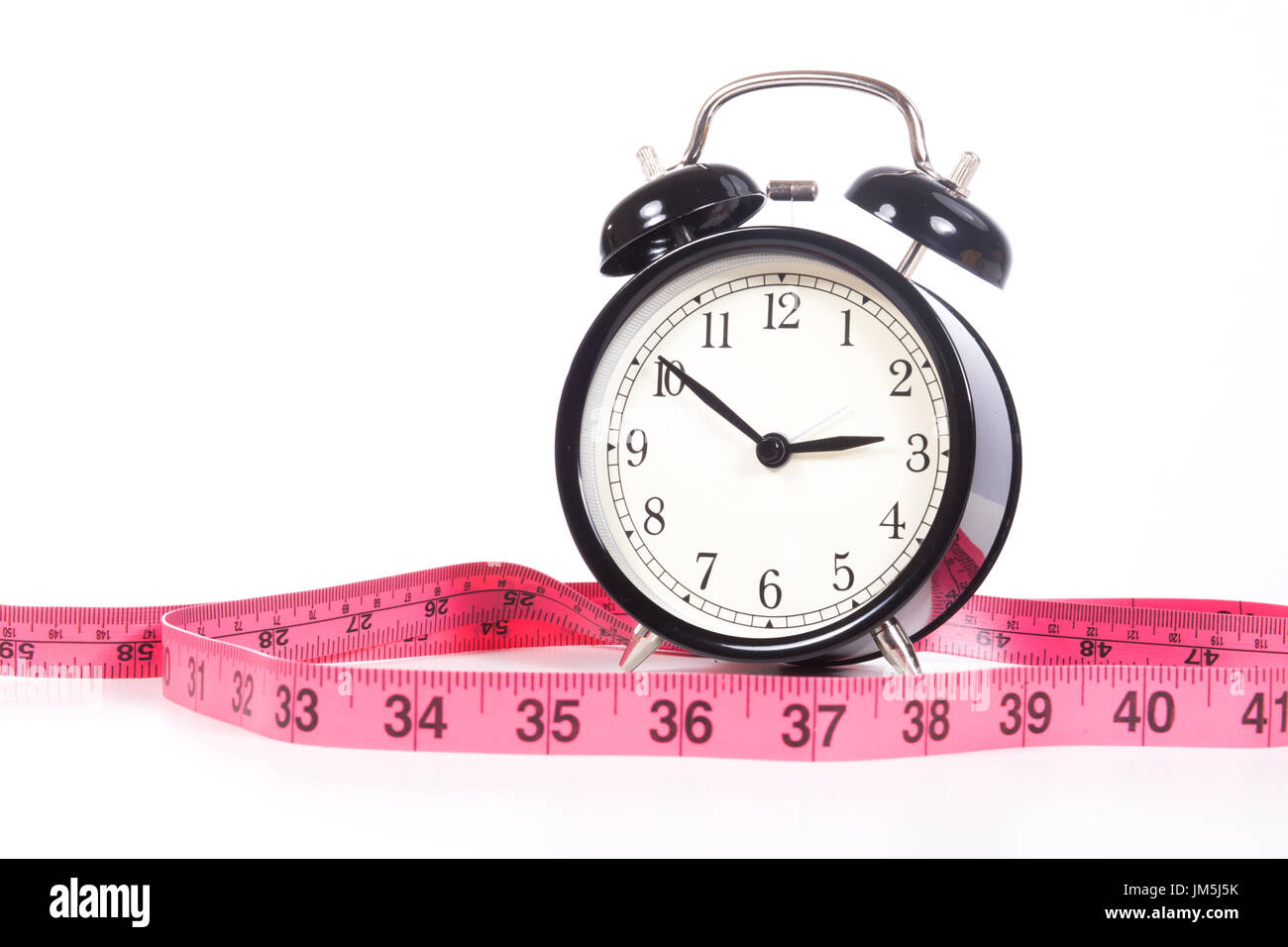 Klassische schwarze Wecker zeigt zehn Minuten drei und Maßband rosa markiert in Zoll, close-up Vorderansicht isoliert auf weißem Hintergrund mit Stockfoto