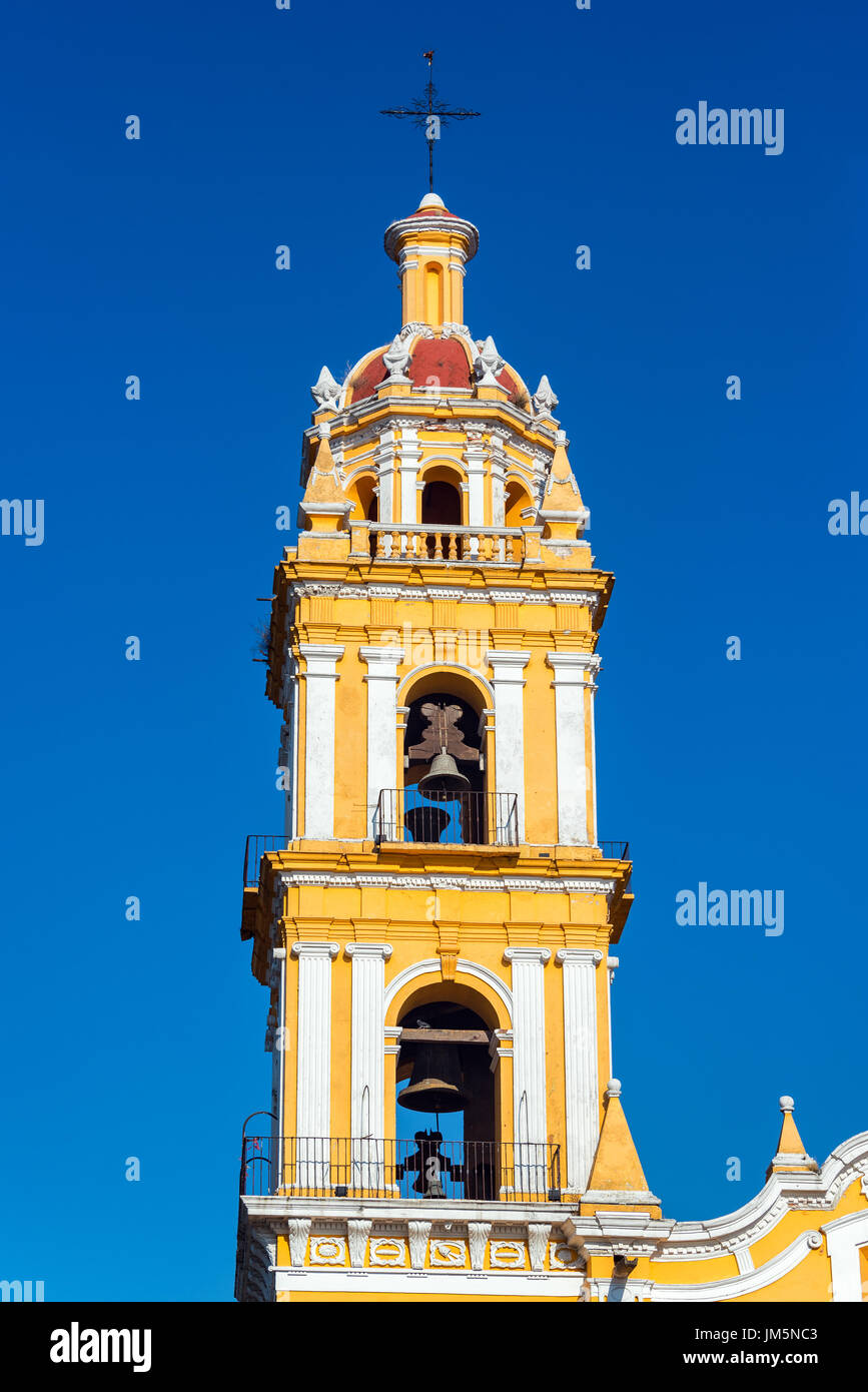 Gelber Turm der Kirche San Pedro in der Mitte von Cholula, Mexiko mit einem tiefblauen Himmel Stockfoto