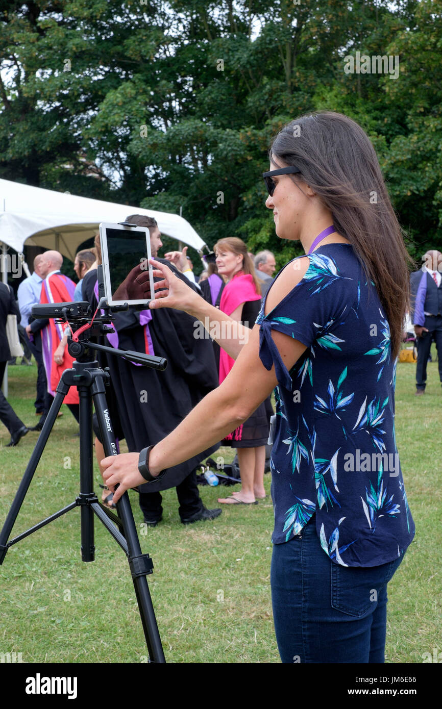 Junge Frau fotografieren und Video über ein i-Pad auf einem Stativ bei einer Abschlussfeier in Portsmouth, England uk montiert Stockfoto