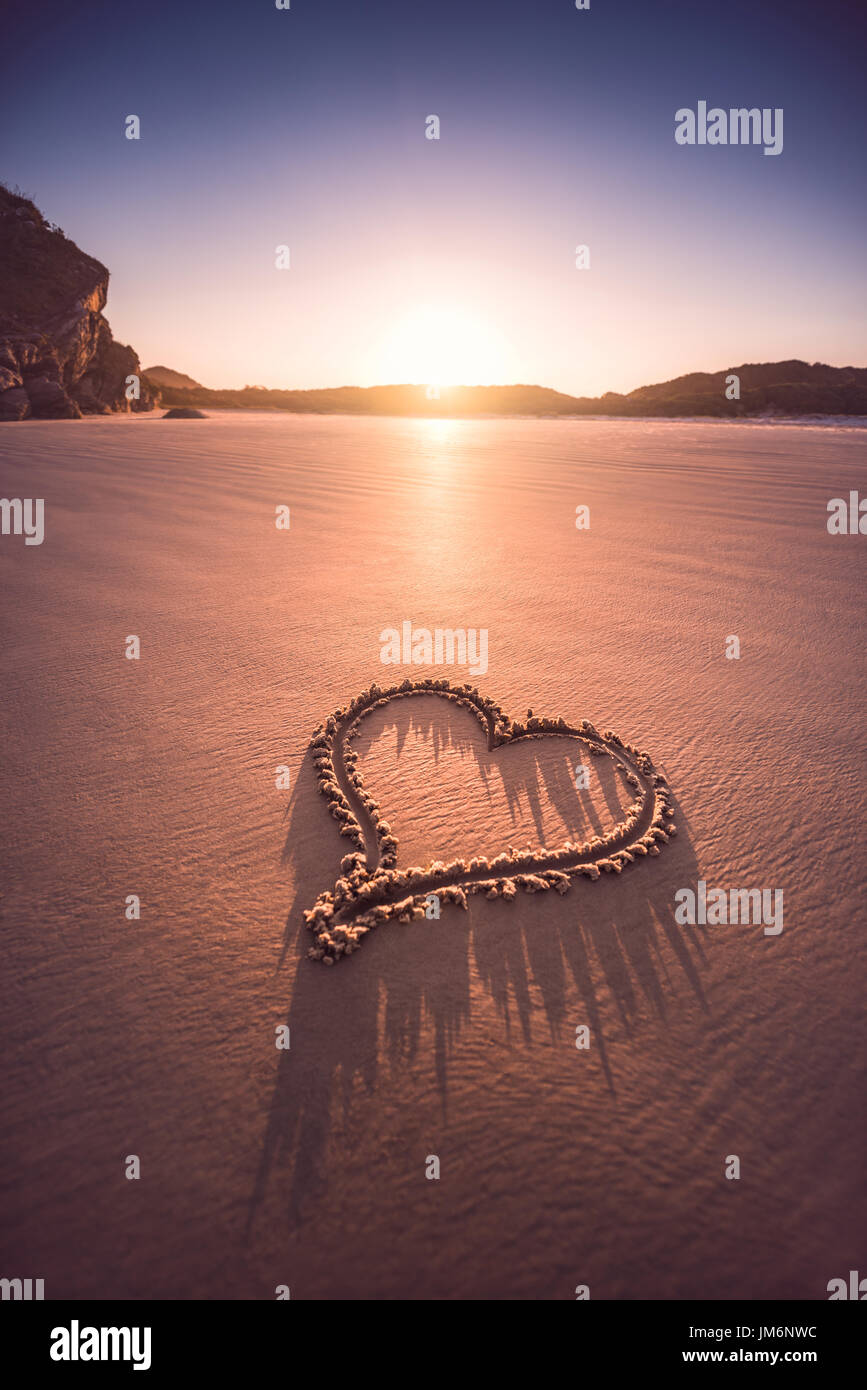 Herz im Sand des Strandes gezeichnet. Valentinstag-Konzept. Stockfoto