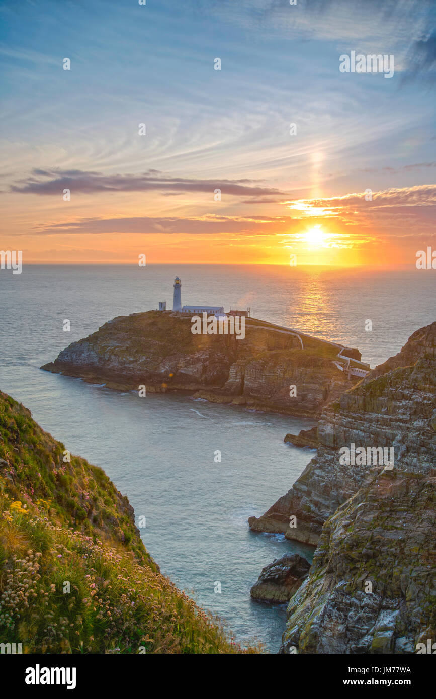 Ein schöner Abend Sonnenuntergang über dem Horizont mit Leuchtturm auf der Klippe. Holyhead, Vereinigtes Königreich. Stockfoto