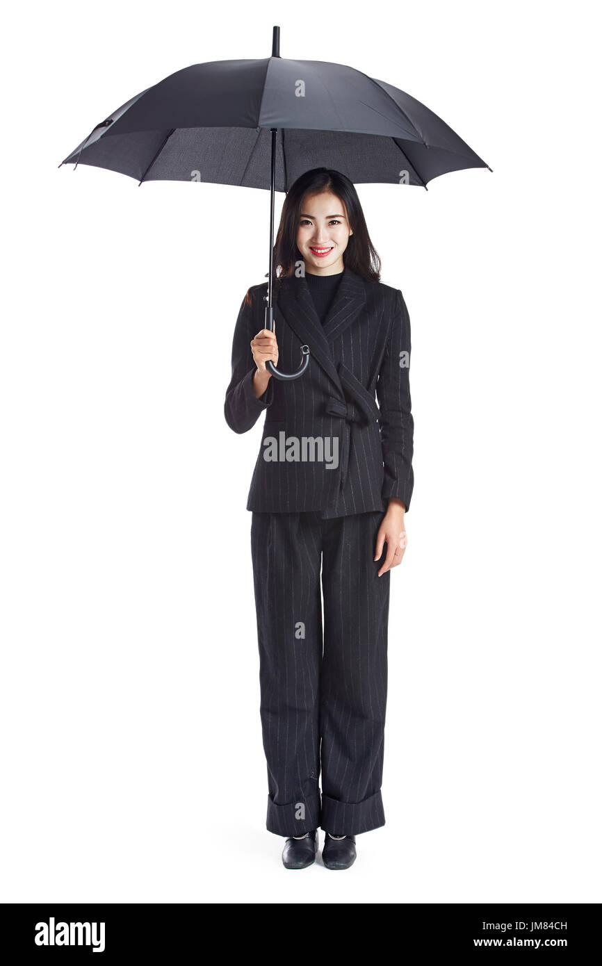 junge asiatische Geschäftsfrau hält ein schwarzer Regenschirm, Blick in die Kamera Lächeln, Studio gedreht, isoliert auf weißem Hintergrund. Stockfoto