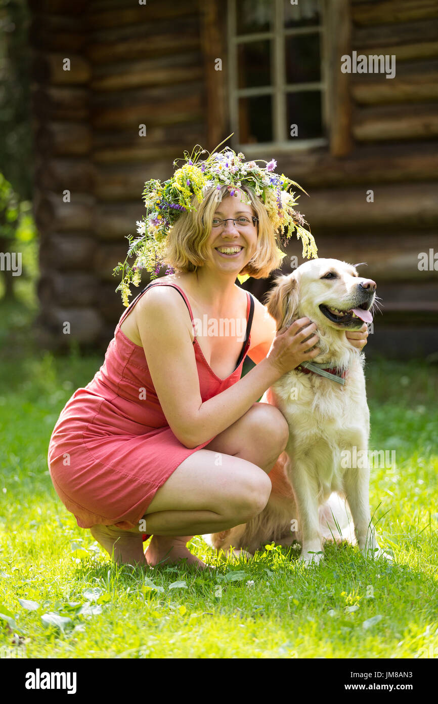 junge Frau mit Kranz auf dem Kopf und einem Hund, golden retriver Stockfoto