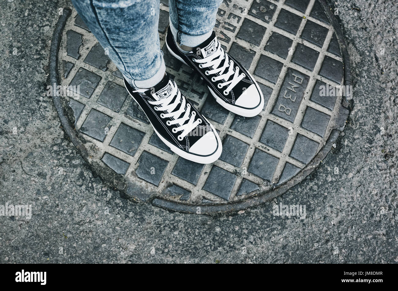Sankt-Petersburg, Russland-30. Mai 2017: Teenager Füße in einem Paar von schwarzem Canvas Freizeitschuhe Chuck Taylor All-Stars auf städtischen Kanaldeckel stehen Stockfoto