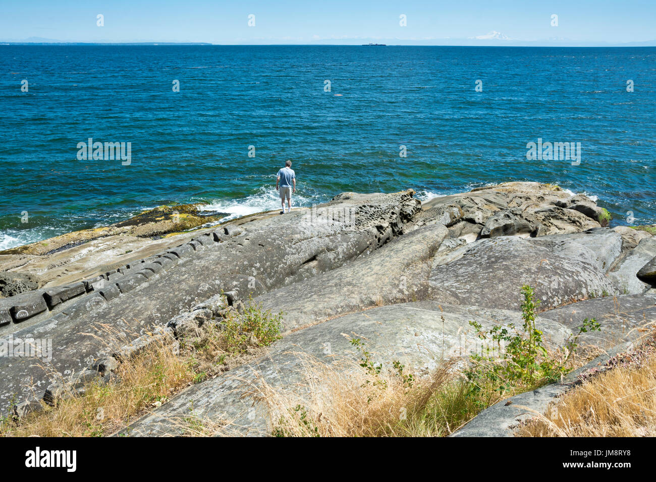 Mann auf Felsformationen am Wasser am Salamanca Punkt Galiano Island, British Columbia, Kanada Stockfoto