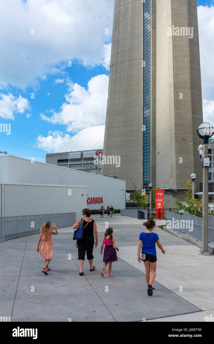 Frau Mutter und drei weibliche Kinder Töchter zu Fuß in Richtung der CN Tower (Basis des Turms sichtbar); besuchenden Sehenswürdigkeiten Toronto an einem sonnigen Tag. Stockfoto