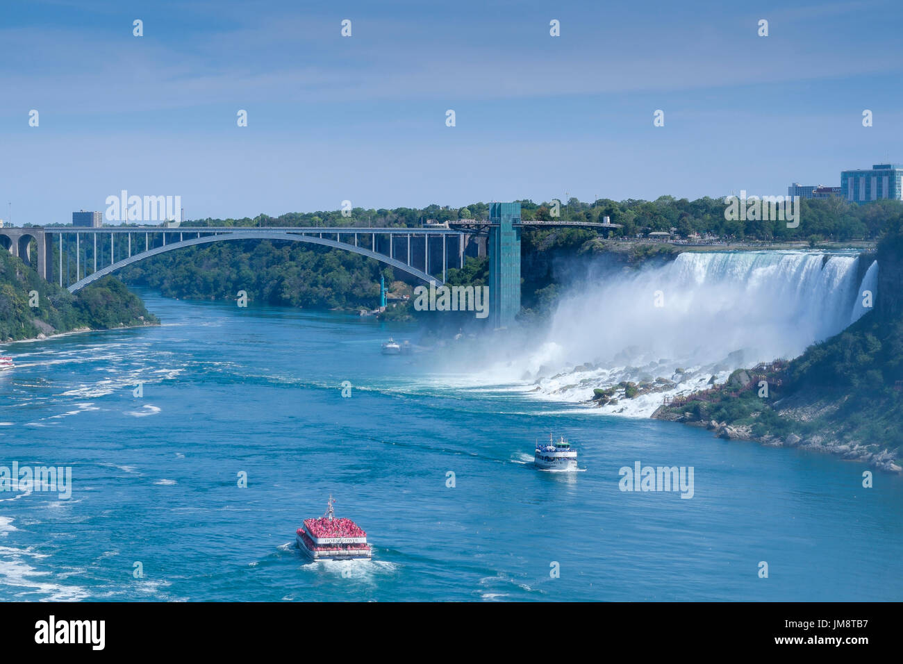 Mit Blick auf die amerikanischen Wasserfälle an den Niagarafällen an einem sonnigen Tag; Hornblower und Magd im Nebel sind auf dem Niagara Fluss. Sonniges Wetter. Stockfoto