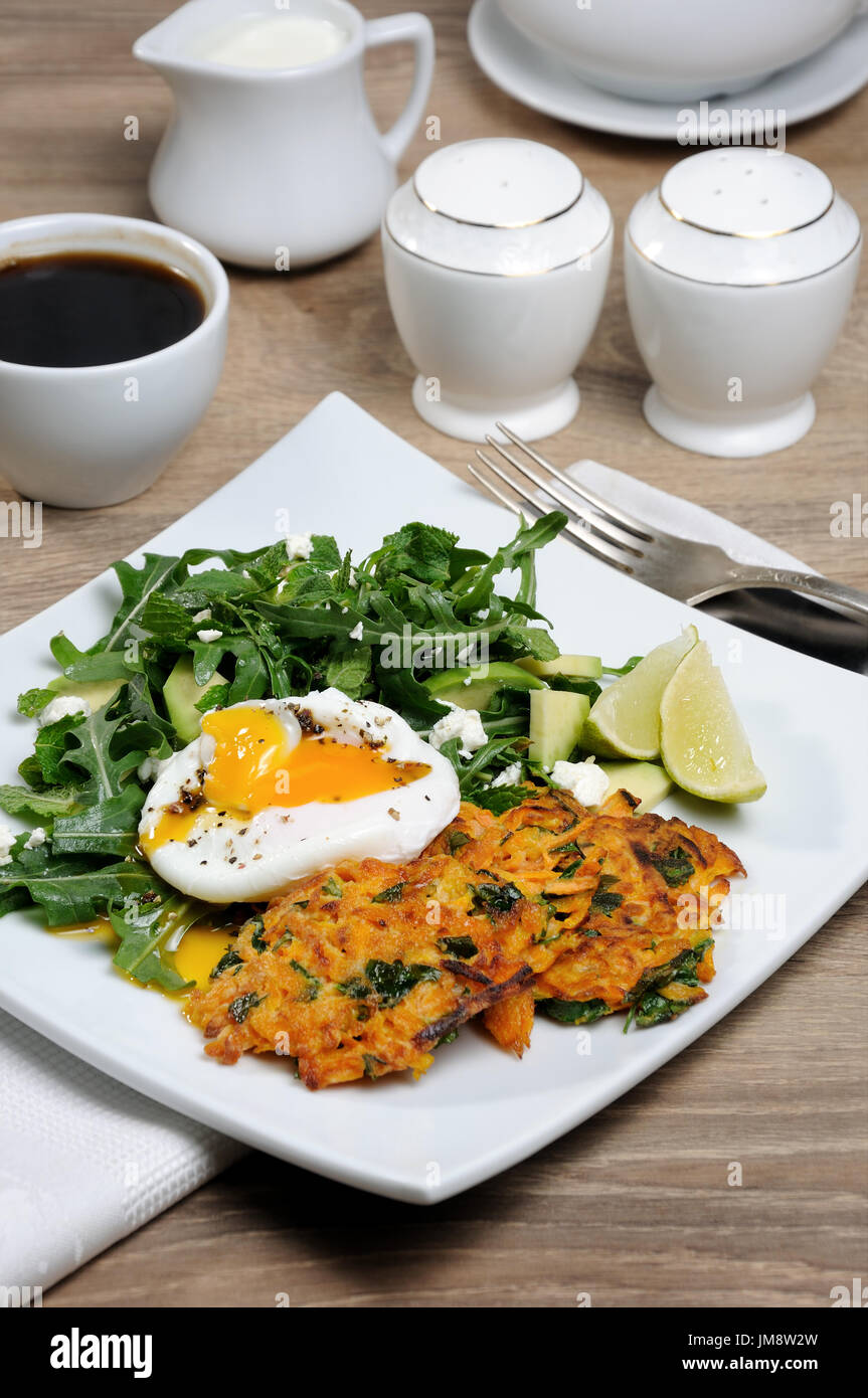 Brunch-Idee. Pochiertes Ei mit Kürbis-Spinat-Pfannkuchen und Garnitur aus Rucola, Avocado, Minze und ricotta Stockfoto