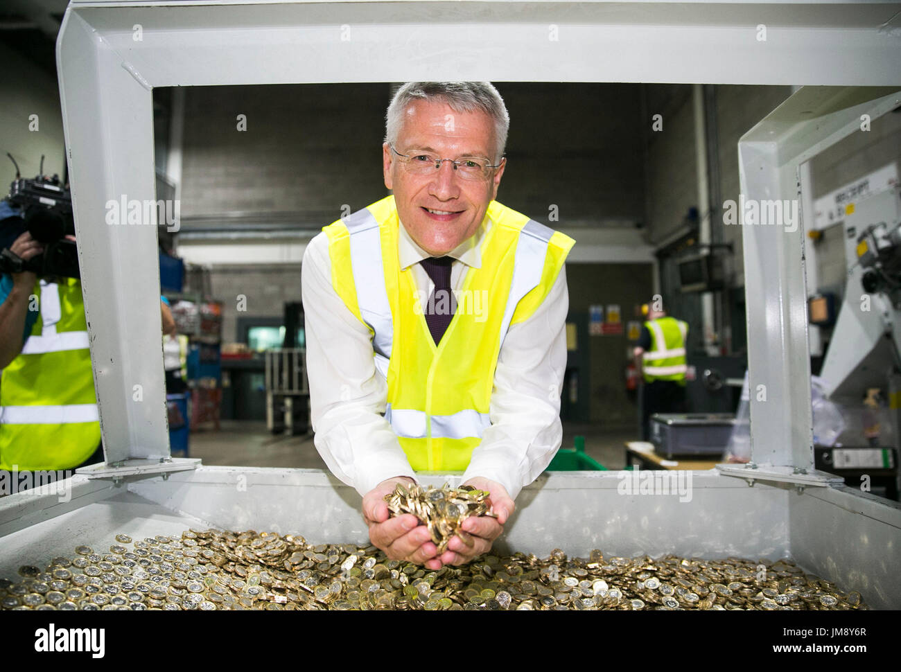 Staatskasse Sekretärin zum Fiskus, Andrew Jones MP holding neue ein Pfund-Münzen bei einem Besuch in der G4S Lösungen Liquiditätsfazilität in Newtownabbey in der Nähe von Belfast. Stockfoto