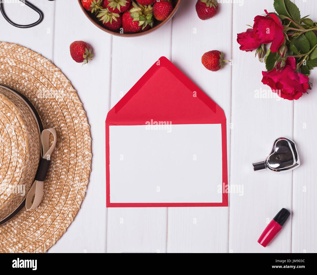 Leeres Papier, Hut, rote Rosen und Erdbeeren auf weißem Hintergrund aus Holz. Sommer-Konzept Stockfoto
