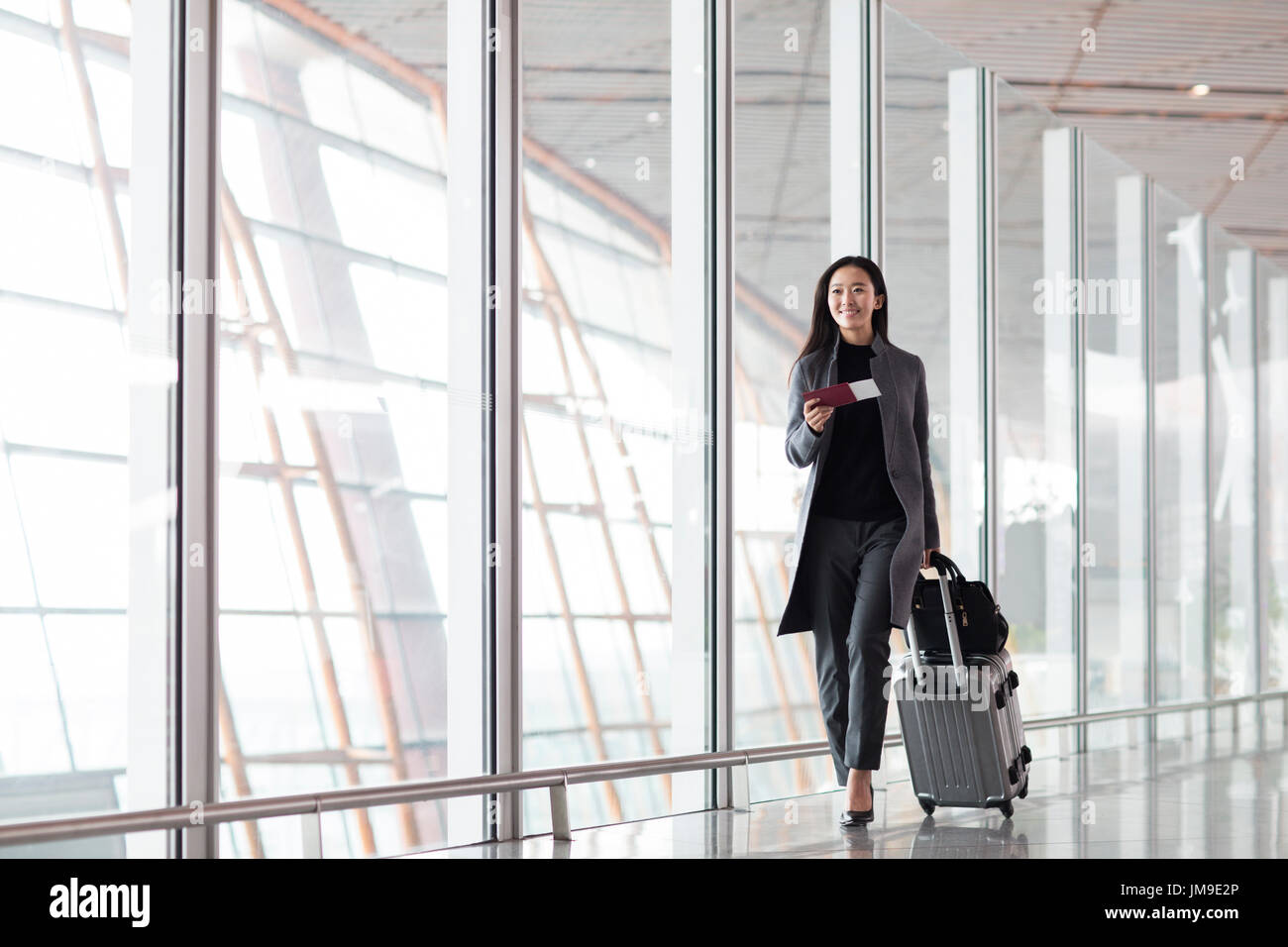 Chinesische Unternehmerin ziehen Rädern Gepäck im Flughafen-lobby Stockfoto