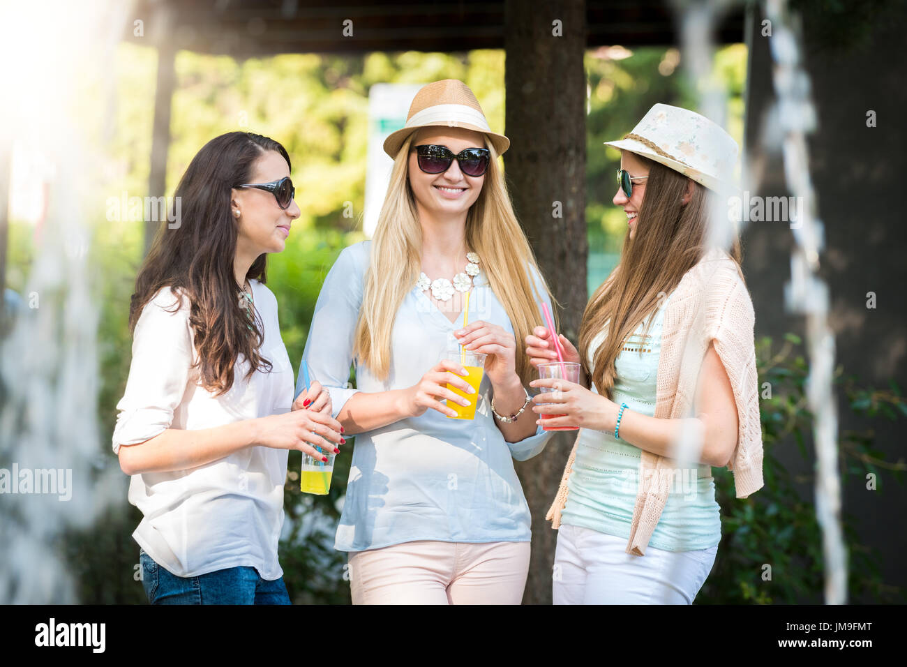 Freundinnen genießen Cocktails von einem Brunnen, Freundschaft-Konzept Stockfoto