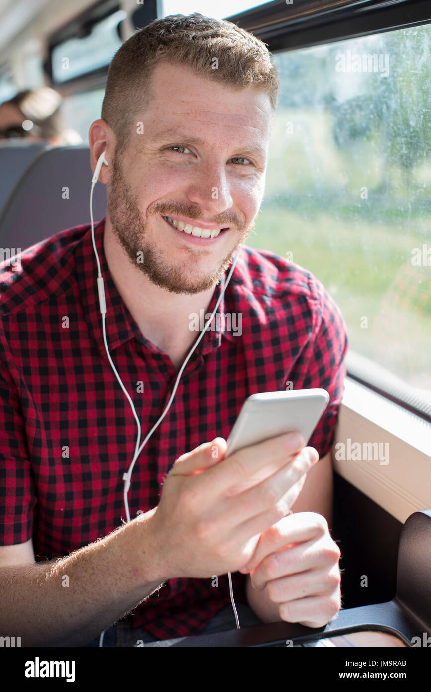 Junger Mann anhören von Musik auf dem Handy während der Fahrt zur Arbeit Stockfoto
