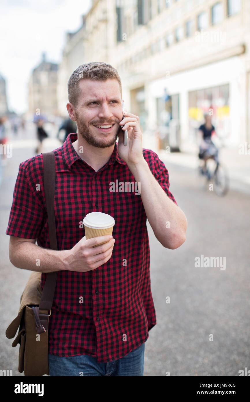 Mann zu Fuß entlang der Stadtstraße telefonieren mit Handy Stockfoto