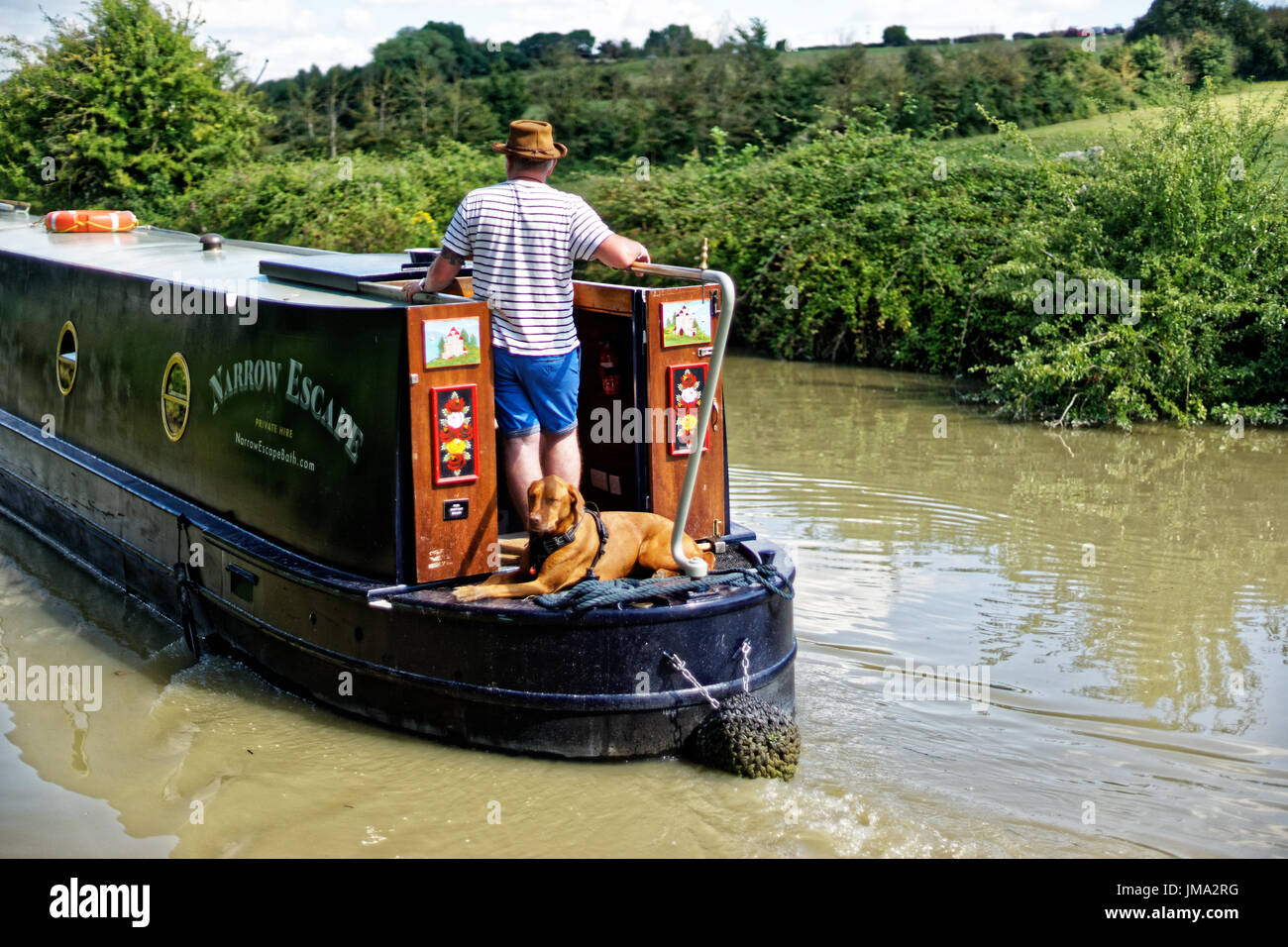 Narrowboat mit Mensch und Hund am Heck Stockfoto