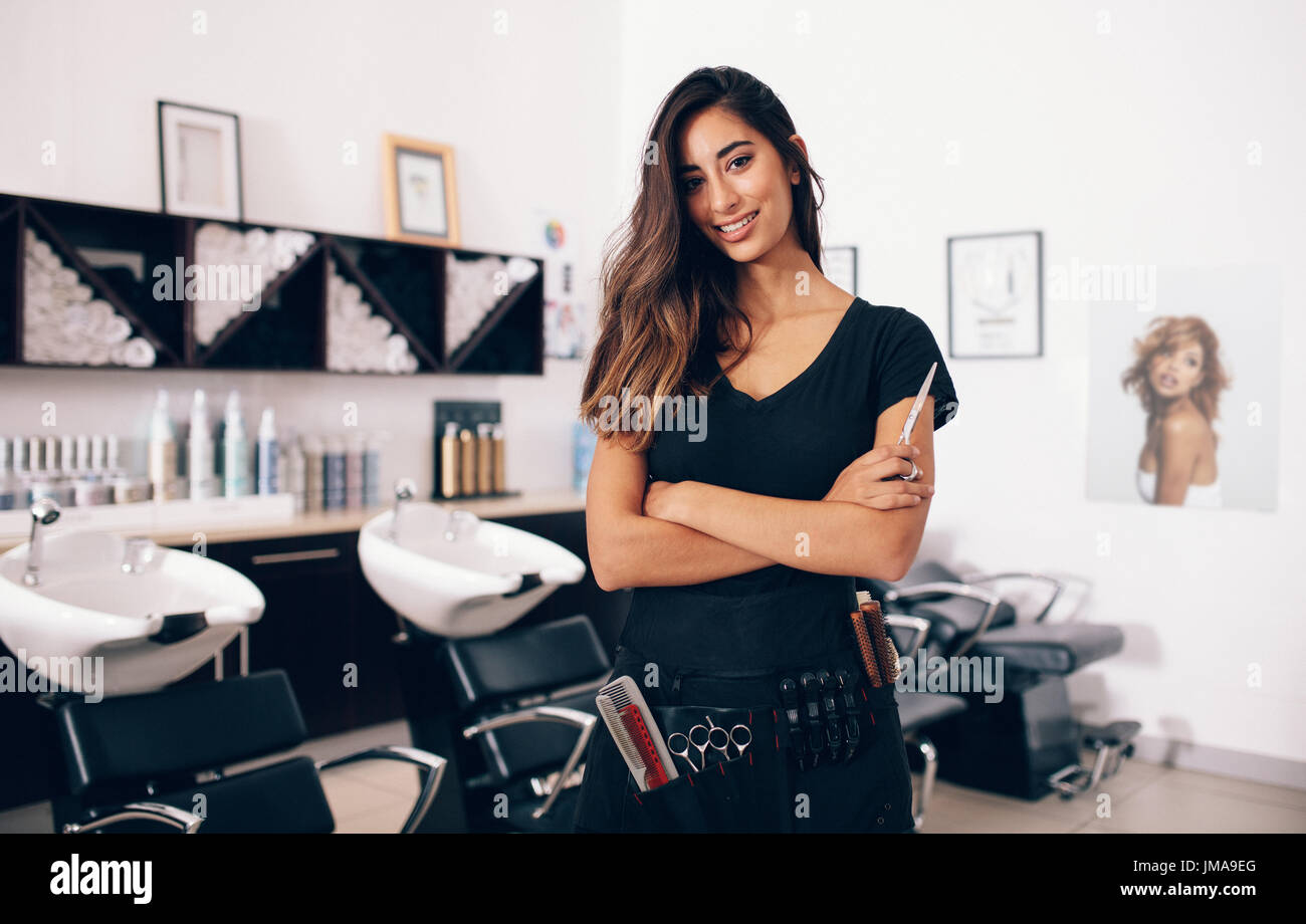 Weibliche Friseur im Salon hält Schere in der hand. Lächelnde junge Friseur im Salon stehen. Stockfoto