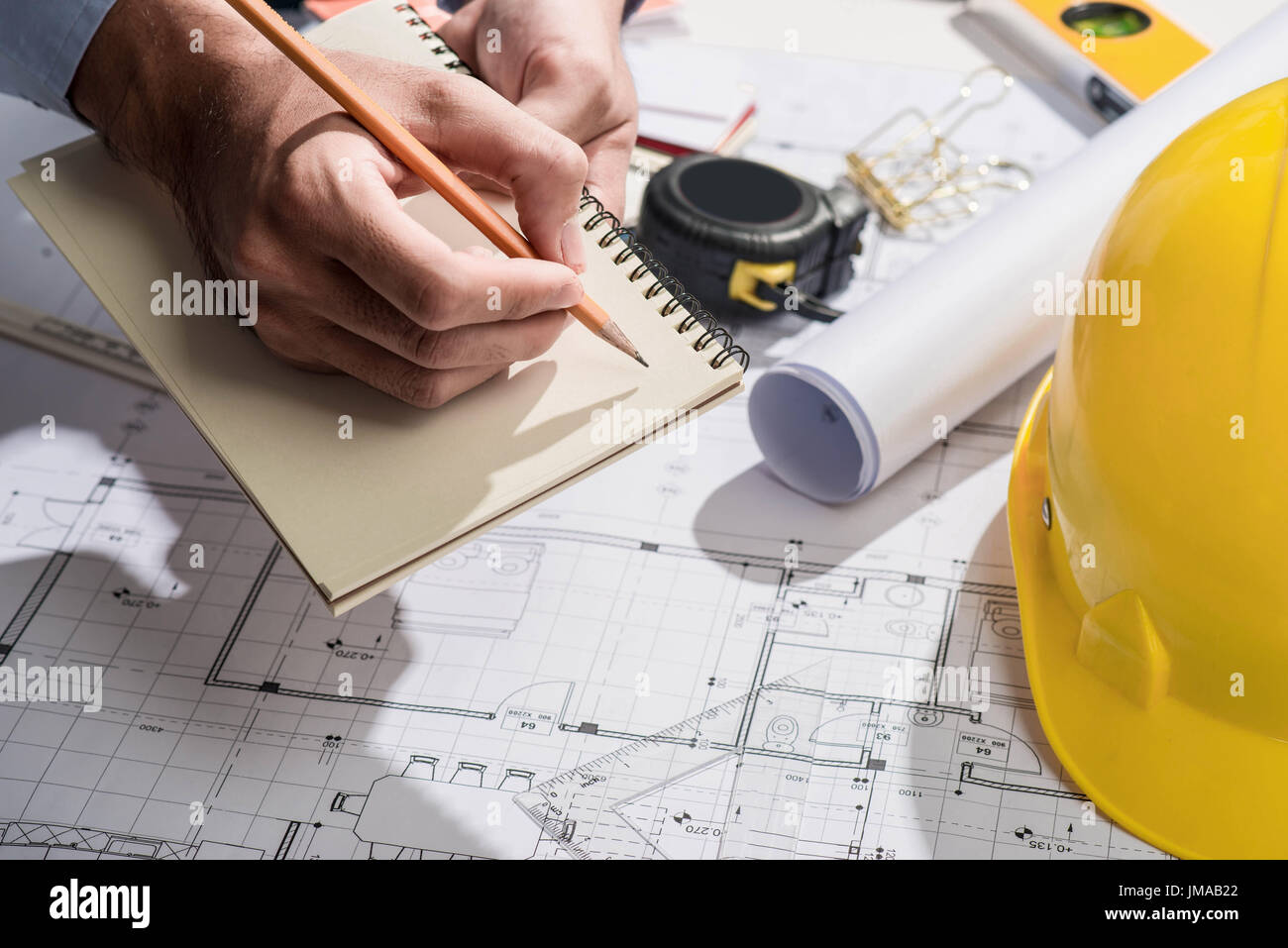 Arbeiten auf Blaupausen. Bauprojekt mit Händen auf Notebook schreiben. Stockfoto