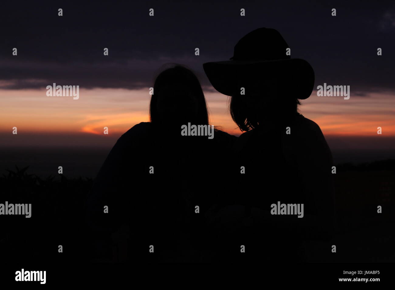 Silhouette der beiden Mädchen in Lima mit dem Sonnenuntergang im Hintergrund Stockfoto