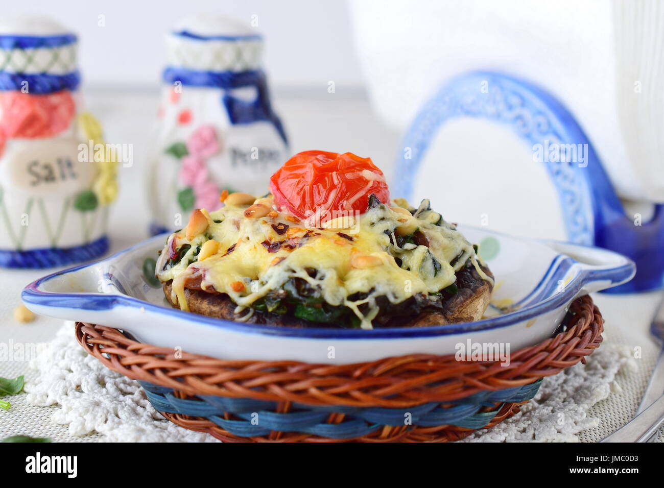 Gegrillte Portobello-Pilze mit Spinat, Pinienkernen, Zwiebeln und Käse in einem Keramiktopf. Gesunde Ernährung-Konzept. Mediterranes Lebensgefühl. Stockfoto