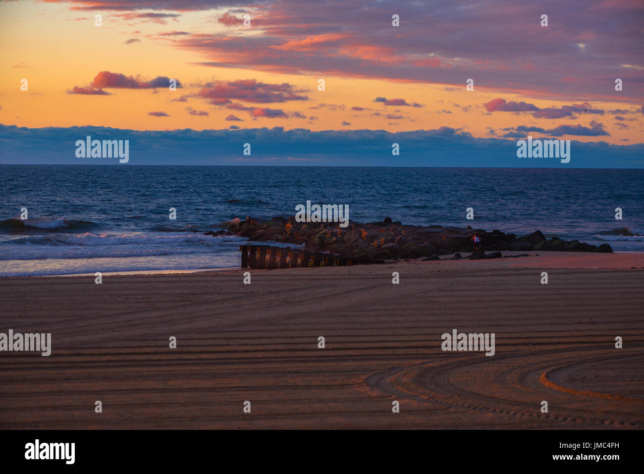 Der Himmel über dem Meer ist eine bunte Kombination aus blau, Orange und Magenta kurz nach Tagesanbruch. Stockfoto