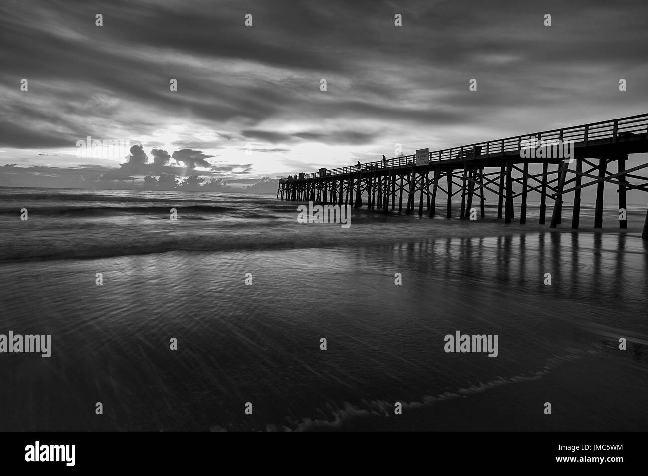 Ein B&W Bild der Sonnenaufgang über dem Atlantik am Pier in Flagler Beach, Florida. Stockfoto