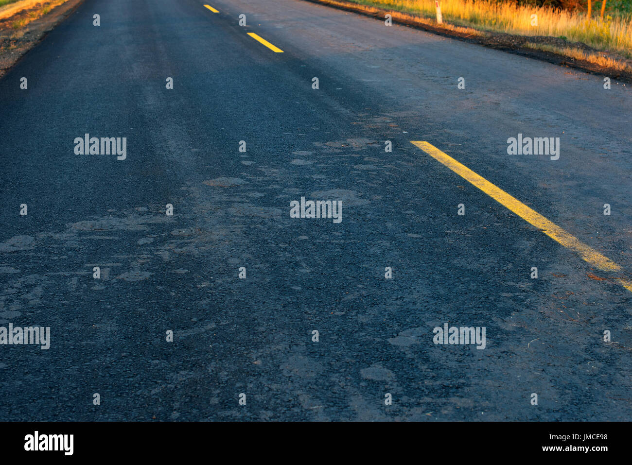 Schlamm-Trails von Traktorreifen auf neuen Asphaltstraße Stockfoto