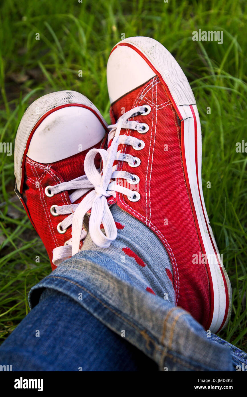 Füße aus roten Sneaks im Freien. Entspannen Sie im Sommer. Stockfoto