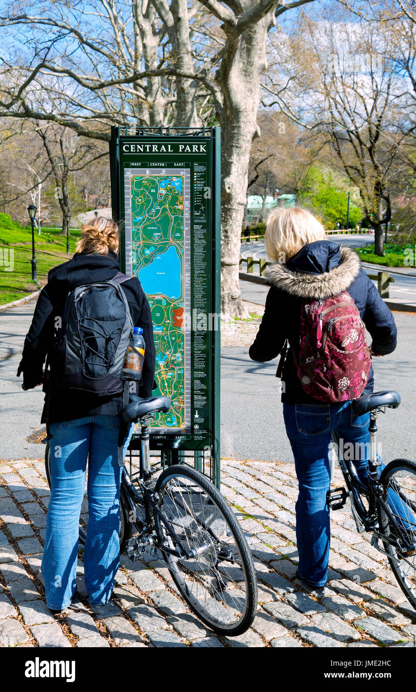 Zwei Frauen auf Fahrrädern im Central Park in New York City, zu stoppen, um zu überprüfen, einen Karte Kiosk für Richtungen Stockfoto