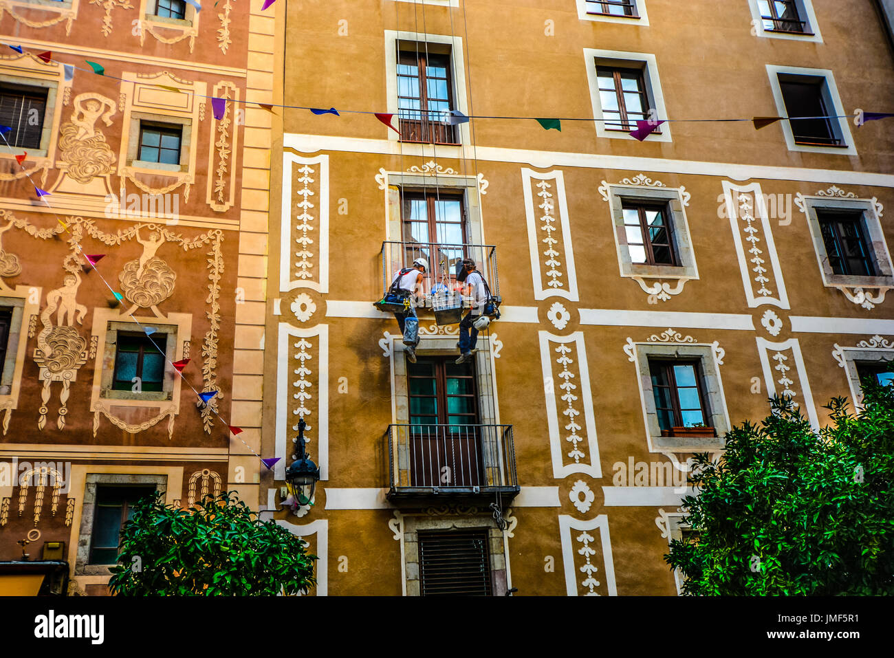 Zwei Bauarbeiter auf Seilen arbeiten auf einer Veranda an der Plaça del Pi im Gotischen Viertel von Barcelona Spanien hängen Stockfoto