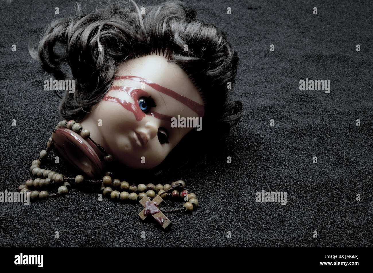 Puppenkopf mit Blut und rosery Kreuz Stockfoto