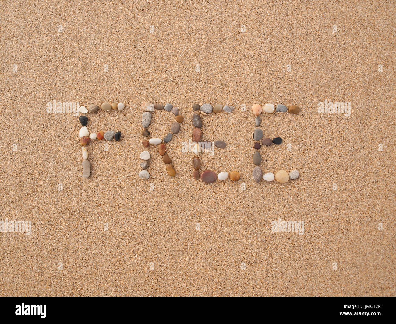 Wort frei geschrieben mit Steinen und Muscheln am Strand am Meer Stockfoto