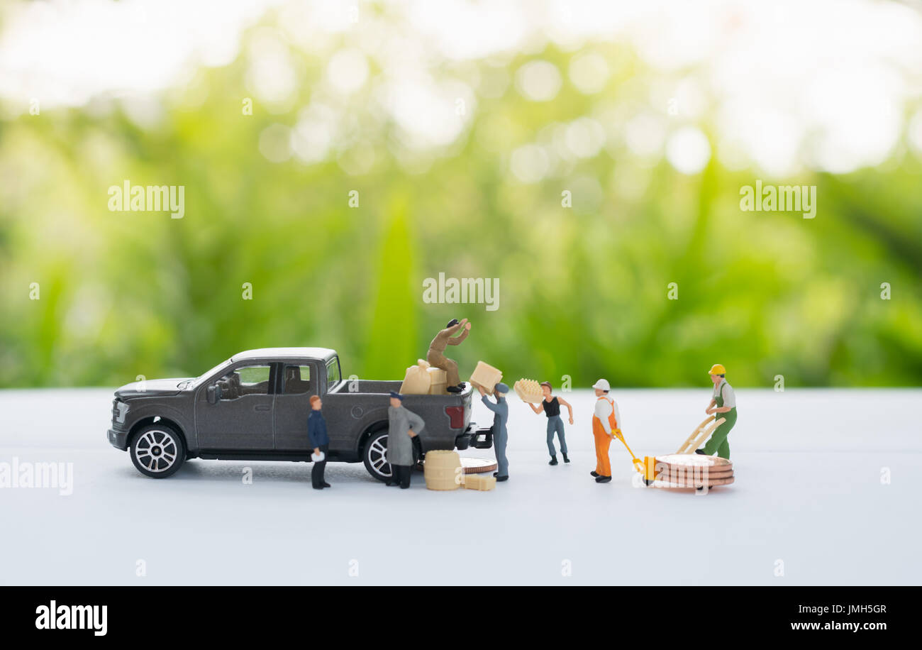 Miniatur-Arbeiter eine Güter befördern Münzen in die kleinen Figuren Auto mit als ein Geschäftskonzept. Stockfoto