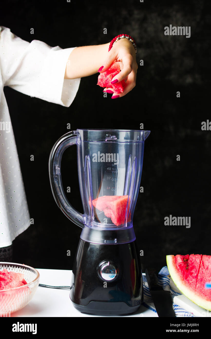 Einfügen von Wassermelone Scheiben in einem Mixer zu einen Smoothie machen weiblich Stockfoto Einfügen von Wassermelone Scheiben in einem Mixer zu einen Smoothie machen weiblich Stockfoto