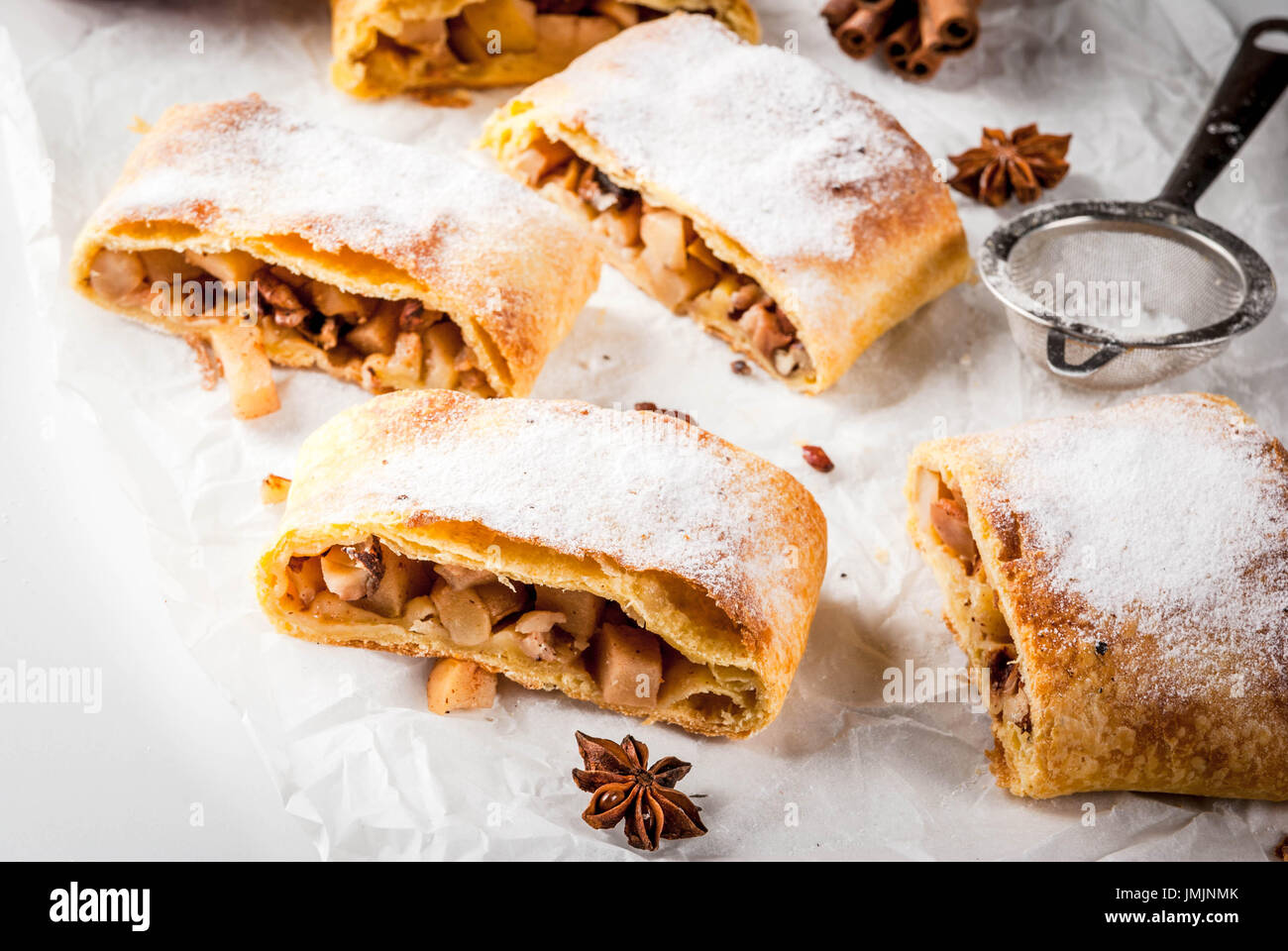 Home Herbst, Sommer, Backen, Blätterteiggebäck. Apfelstrudel mit Nüssen, Rosinen, Zimt und Puderzucker. Auf weißen Marmor Tisch. In Scheiben geschnitten, mit ingredie Stockfoto