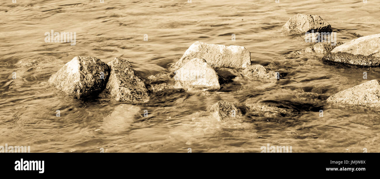 Steinen aus dem Wasser schauen. Bild ist hell und Sepia getönt. Stockfoto