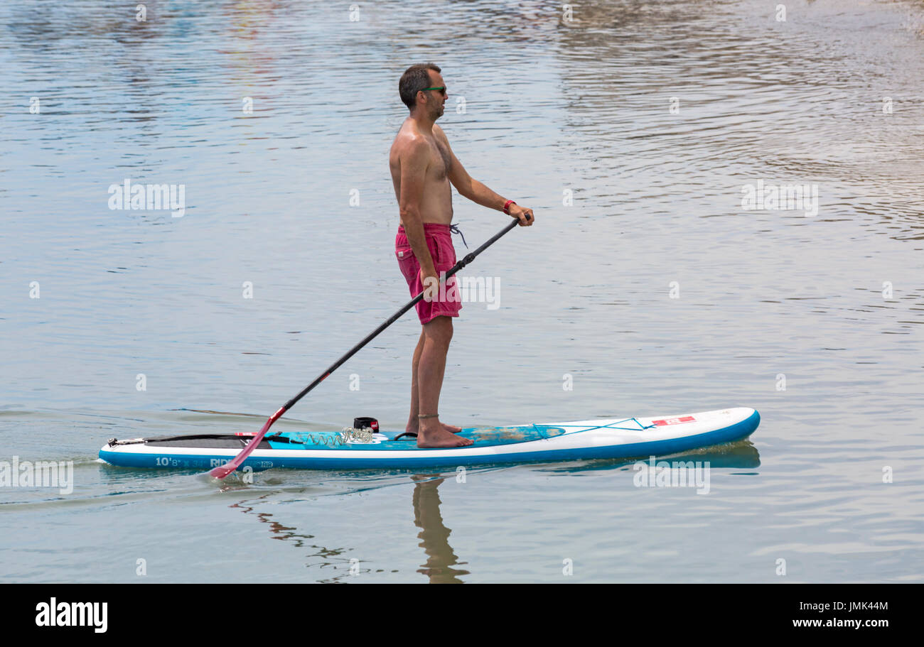 Stehen Sie Paddleboarder-Paddel-Boarder bei Lyme Regis, Dorset im Juli auf Stockfoto