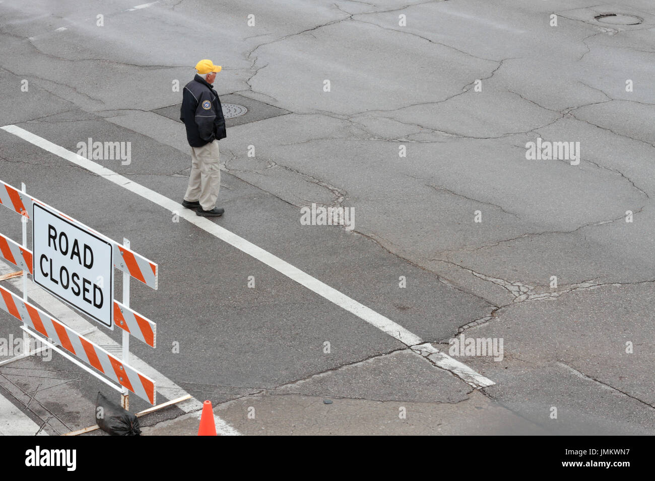 Ein Arbeiter der Stadt steht in einem leeren nasse Straße neben einem Straßenschild geschlossen. Stockfoto