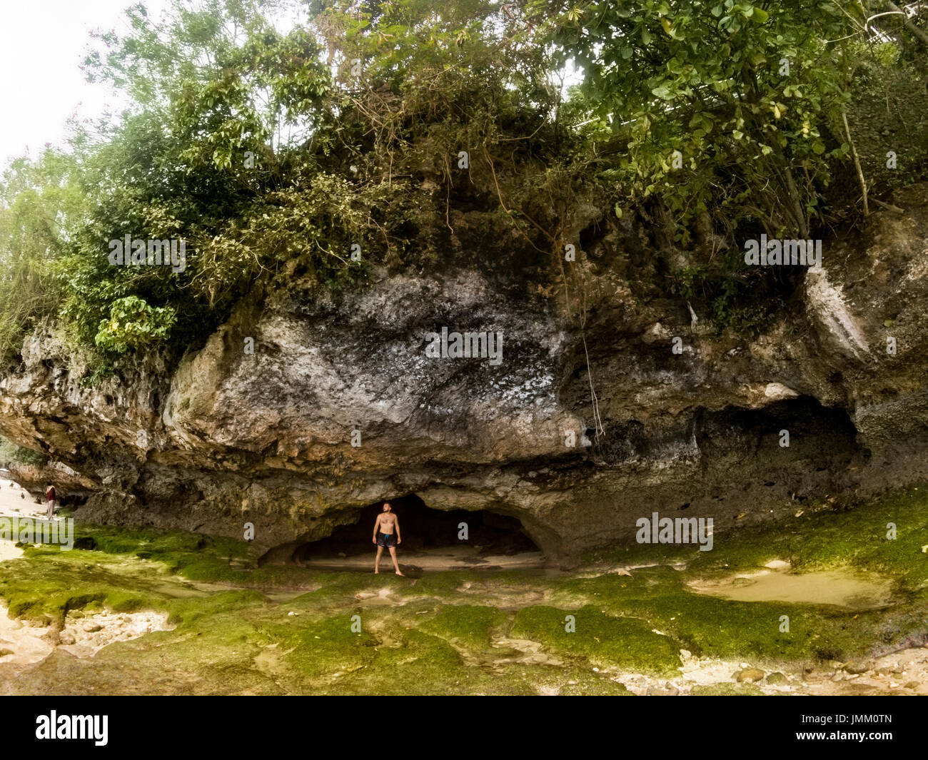 Bali, Indonesien - Juli 10, 2017: ein Mann, der vor der Höhle am Strand von Padang Padang nach tide Ozean Bali Indonesien. Stockfoto