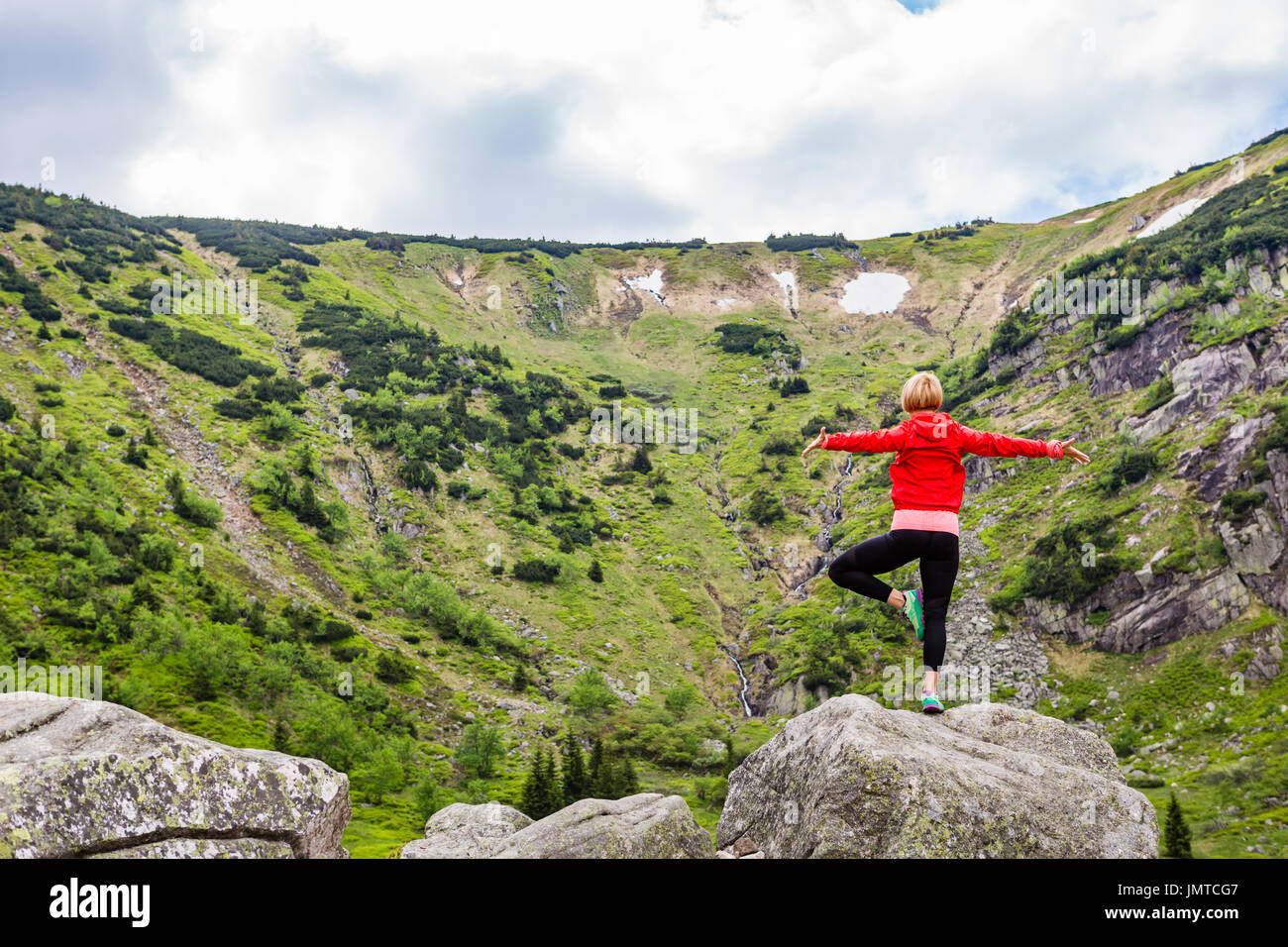 Frau in Yoga-Pose vor der Bergsee zu meditieren. Weibliche Wanderer in inspirierende Berge Landschaft entspannen. Gesunde Lebensweise zu übertreffen Stockfoto
