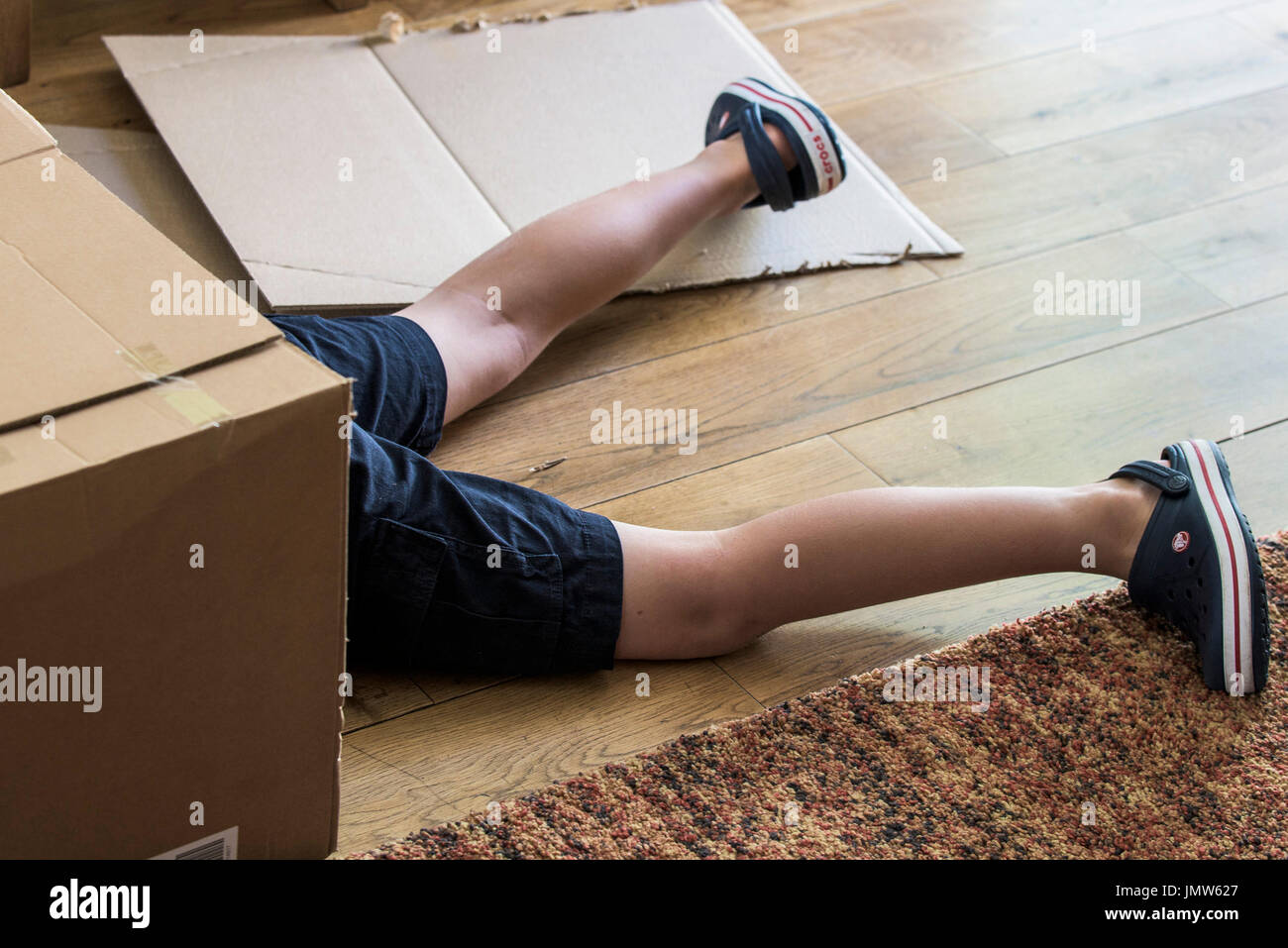 Die Beine eines kleinen Jungen aus einem Karton kleben. Stockfoto