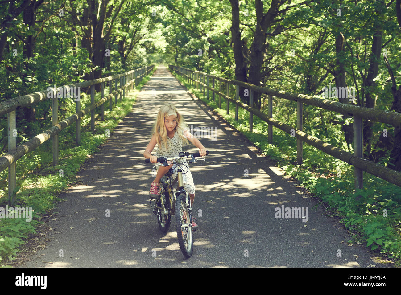 Kind blondes Mädchen mit dem Fahrrad auf einem Radweg im Sommer Stockfoto